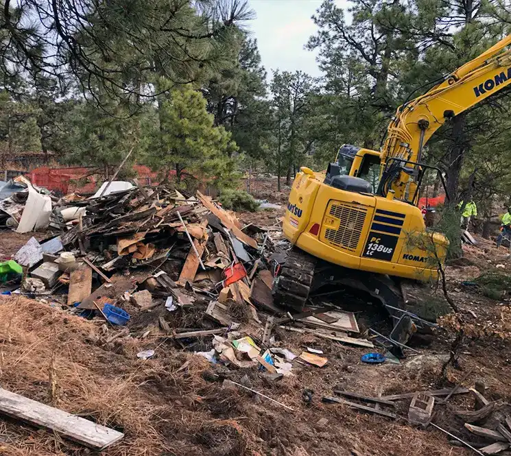 Excavator clearing a demolition site with debris and rubble.