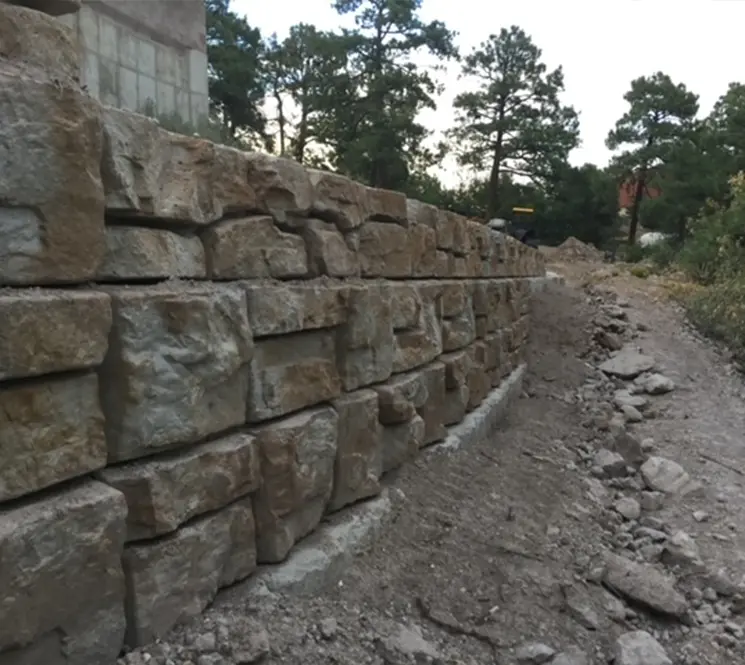 A close-up of a textured retaining wall made from large, natural stone blocks.