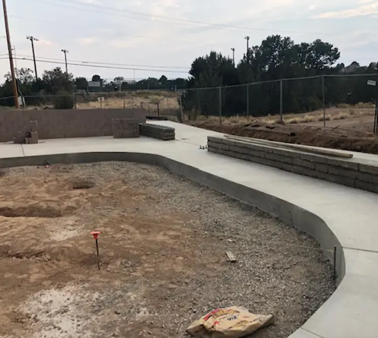 A newly built concrete walkway curving around a construction site with block walls.