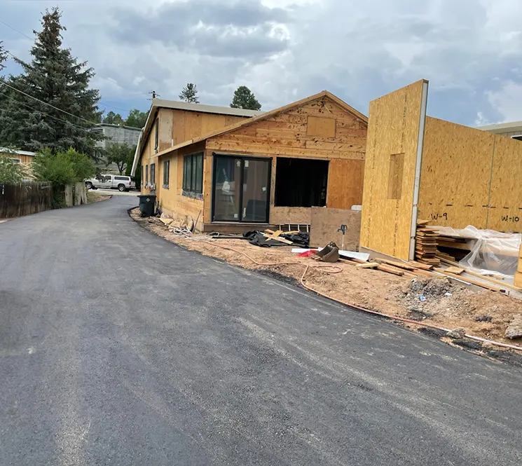  Freshly paved driveway next to a house under construction.