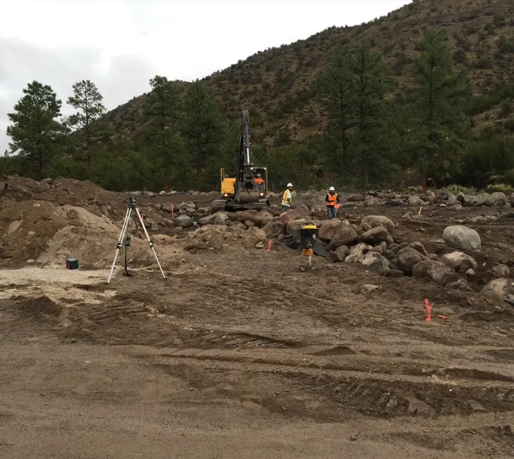 A rocky construction site with heavy machinery and workers preparing the ground for development.
