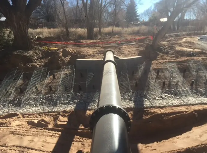 A large pipeline installation project with erosion control measures and a reinforced embankment in a rural setting.